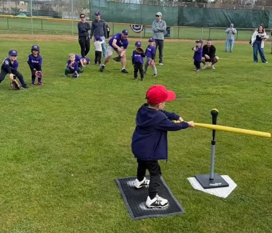 Wiffle Ball player at bat with teammates and coaches
