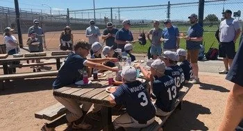 Teammates and families eating lunch together at a picnic table